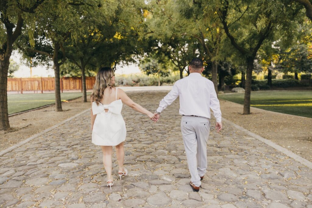 Engaged couple walking along a cobblestone path at Cardella Winery