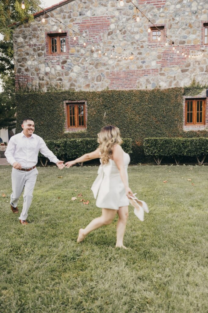 Couple running through the grass in front of beautiful Ivy walls and brick architecture. 